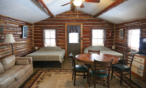 Alternate view of small cabin main room with two queen beds, fold out couch, table and chairs.