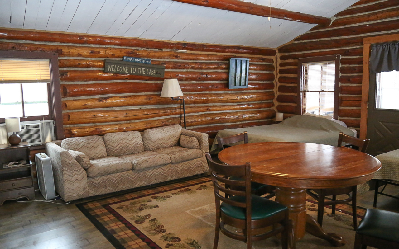 View of cabin living room featuring a fold out couch and table with chairs.