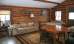 View of cabin living room featuring a fold out couch and table with chairs.