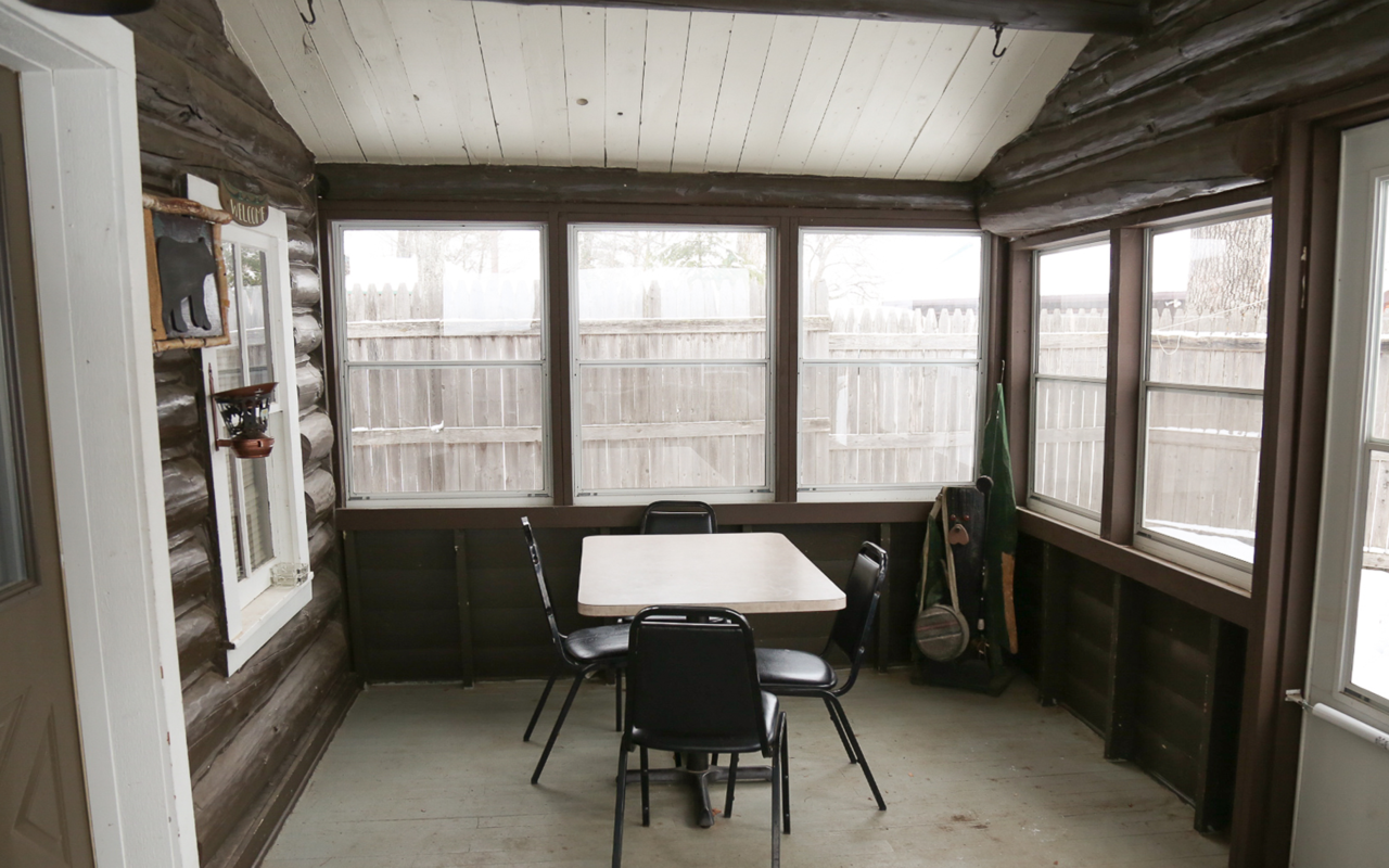 View of three season screened in porch with table and chairs.