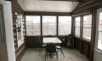 View of three season screened in porch with table and chairs.