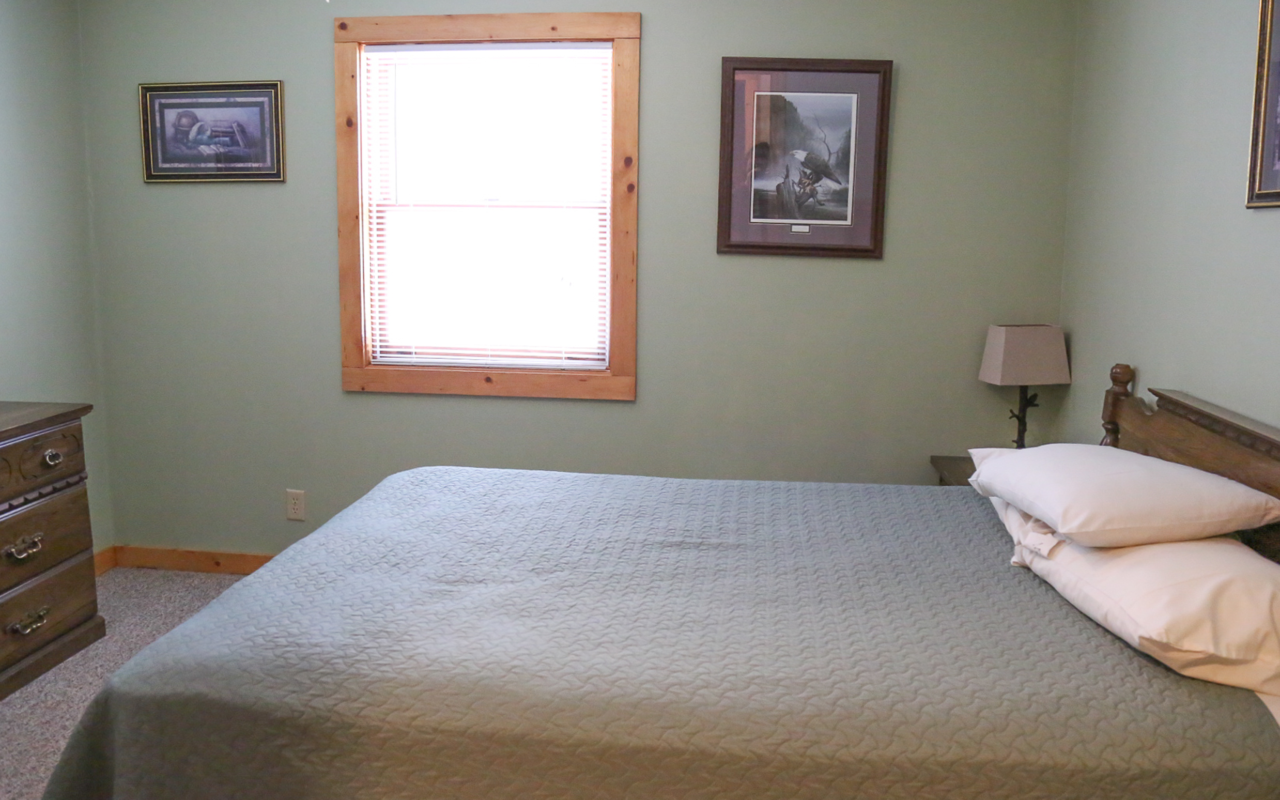 Interior cabin view of bedroom with queen bed.
