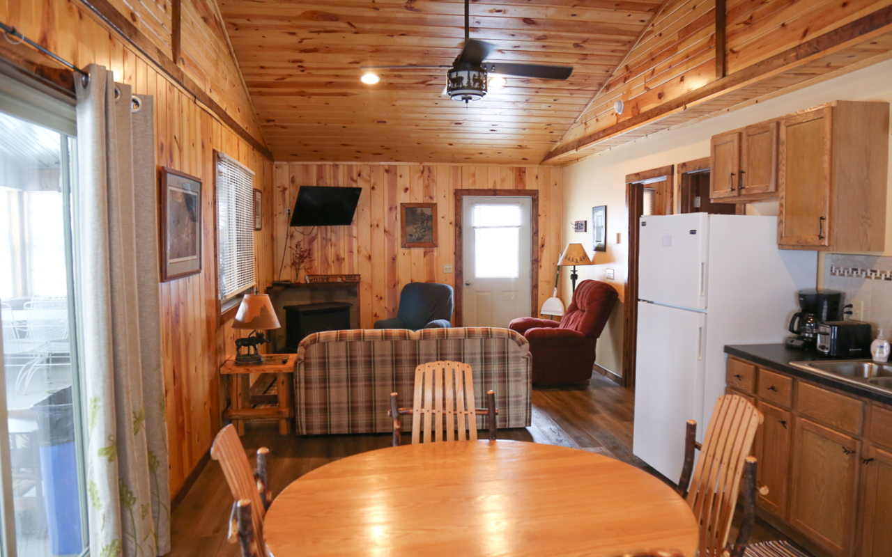 Interior long cabin view of sit in kitchen and living room space.