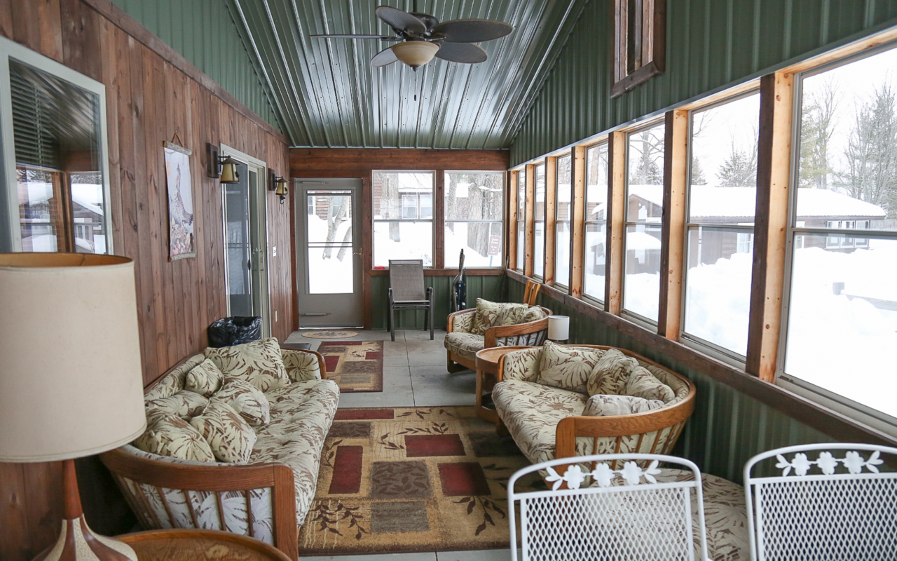 View of screened in porch with several seating areas.
