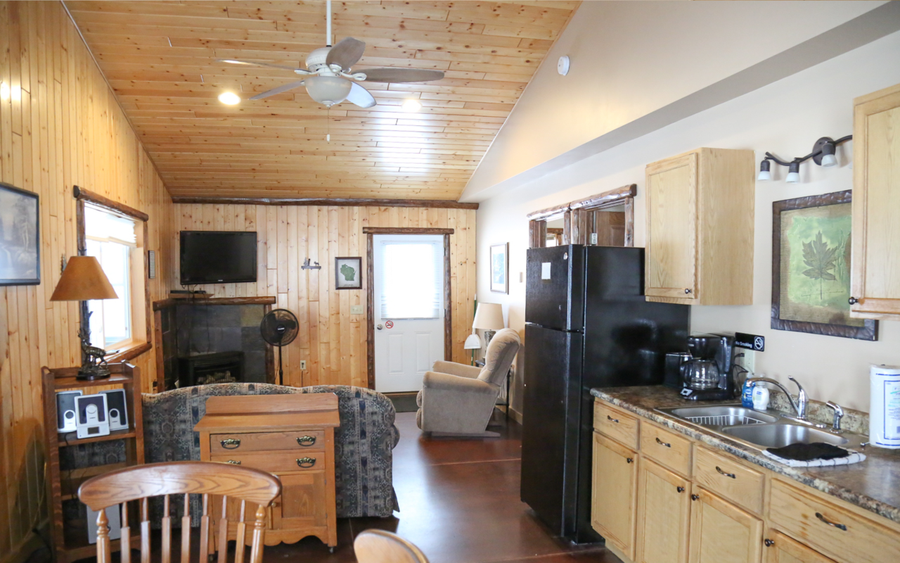 Long view of cabin interior of kitchen, and sitting area.